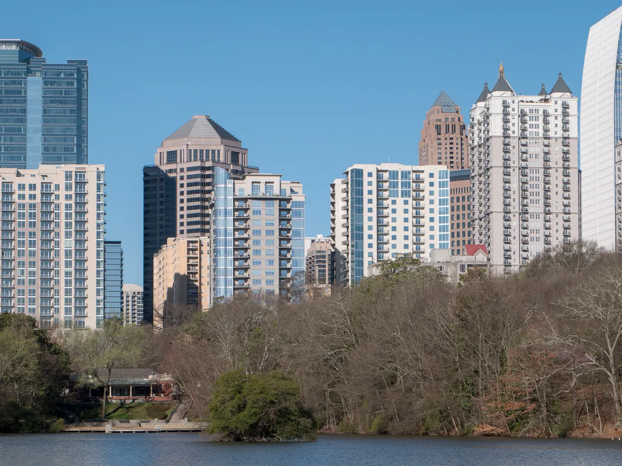 The towers of Midtown Atlanta rising above the trees of Piedmont Park, across Lake Clara Meer